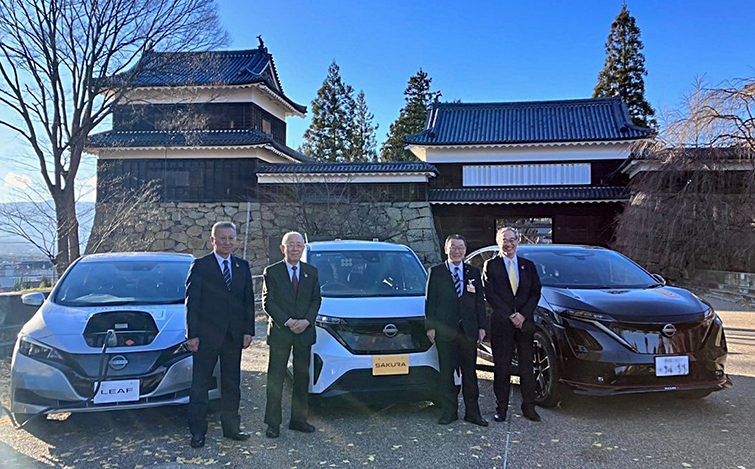 電気自動車の前で記念撮影する各代表者