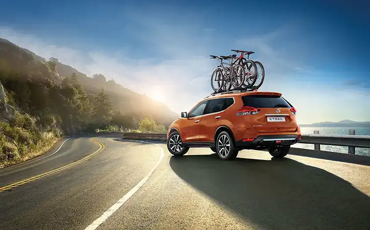 Nissan X-Trail parked on a road with bikes on top.