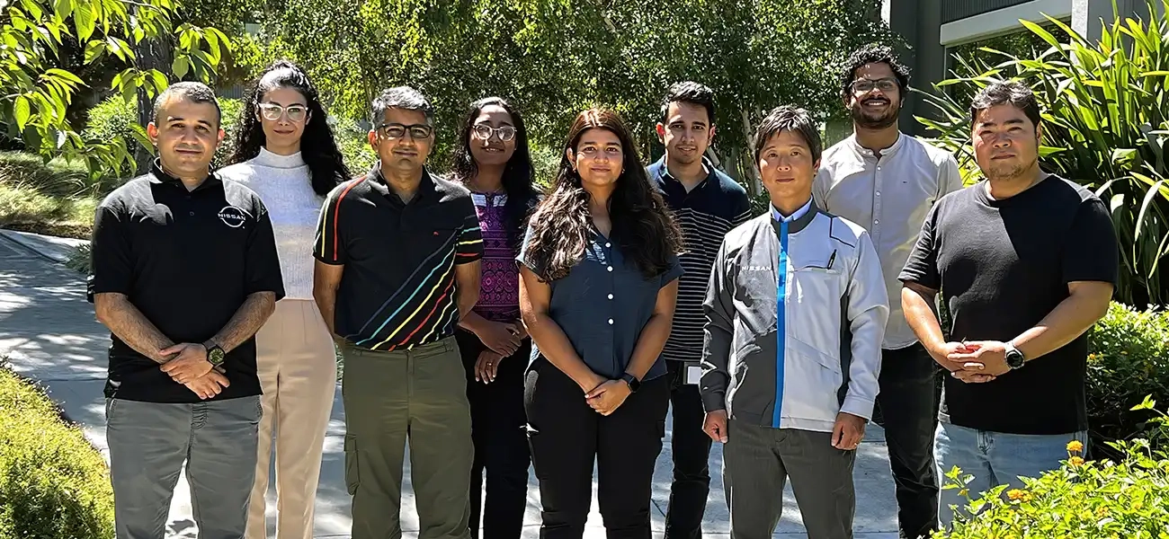 A group of people pausing for picture in front of trees.