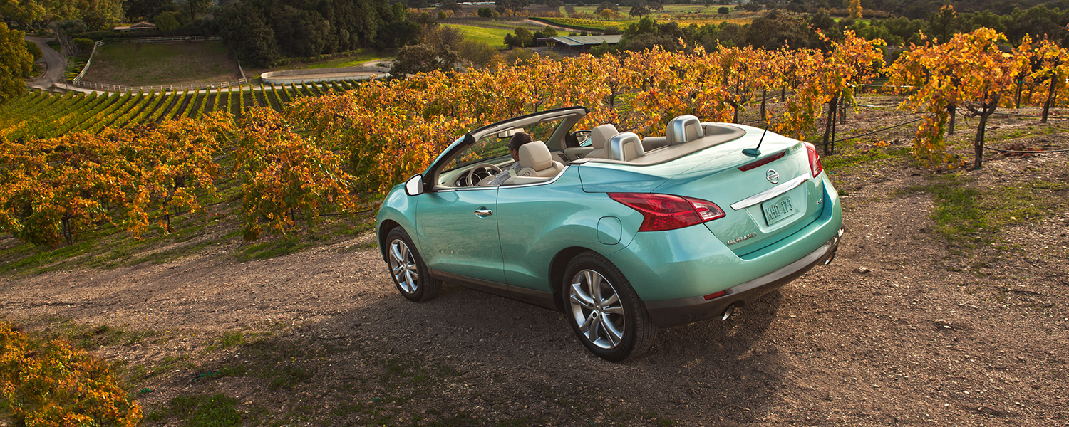 A teal colored Nissan Murano CrossCabriolet with the top down parked on a field.
