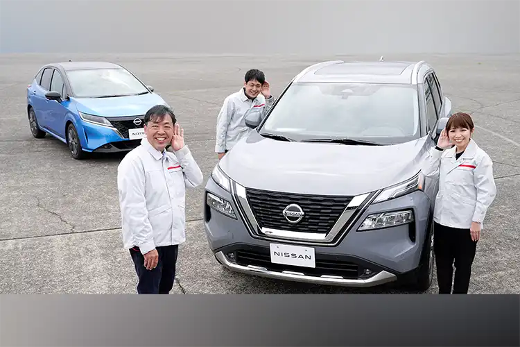 Três pessoas posando para foto com 2 carros