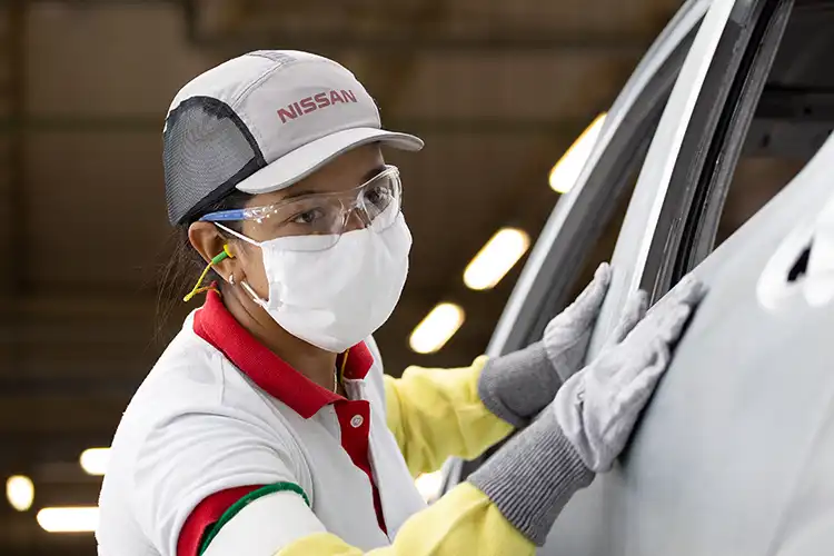 Uma pessoa verificando um carro na linha de montagem