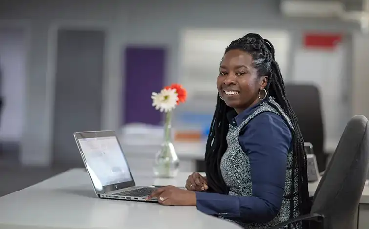 Mpume Cele smiling for the camera while sitting at a desk