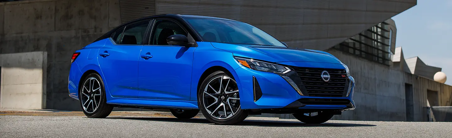 A blue 2024 Nissan Sentra parked outside a building.
