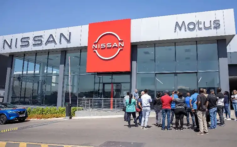 A group of people pose for a photo in front of a dealership
