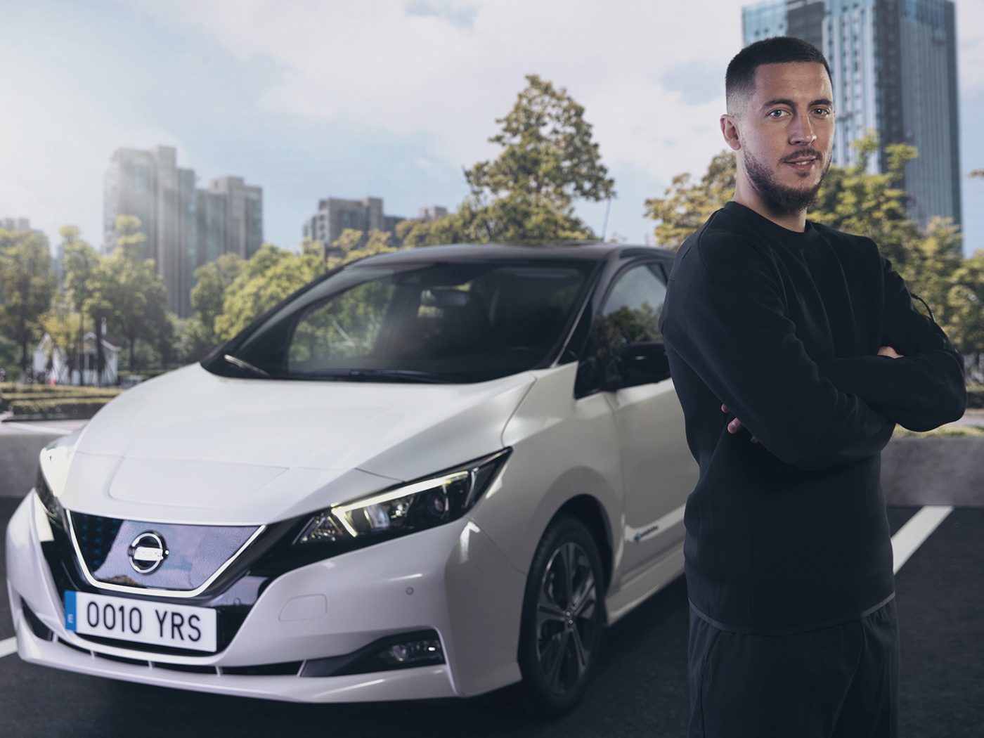 Un hombre se detiene frente a un Nissan LEAF blanco.