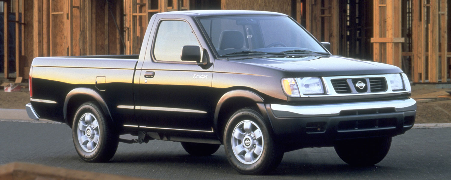 A black Nissan Frontier parked in front of a house being built.