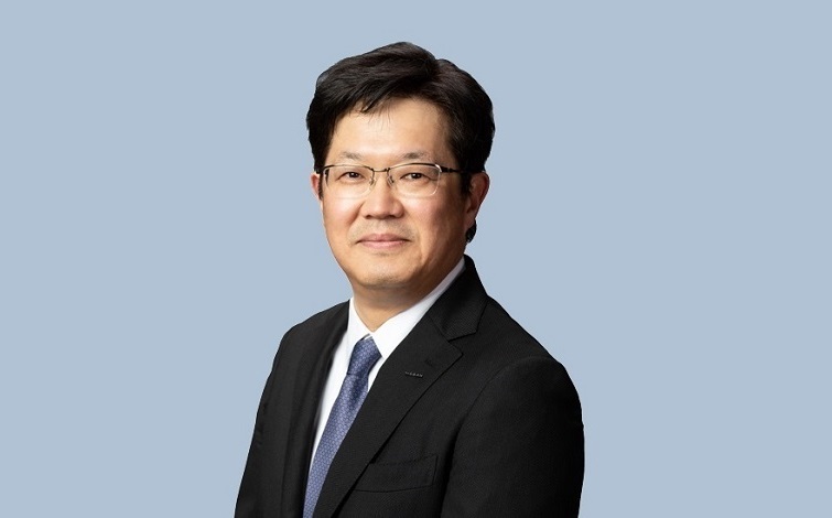 日産自動車常務取締役 やまぐち たけし（水色の背景に黒いスーツ/青いネクタイ、メガネ姿）