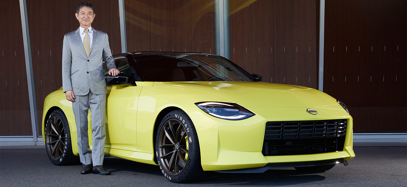 Hiroshi Tamura pausing next to yellow Nissan Z.