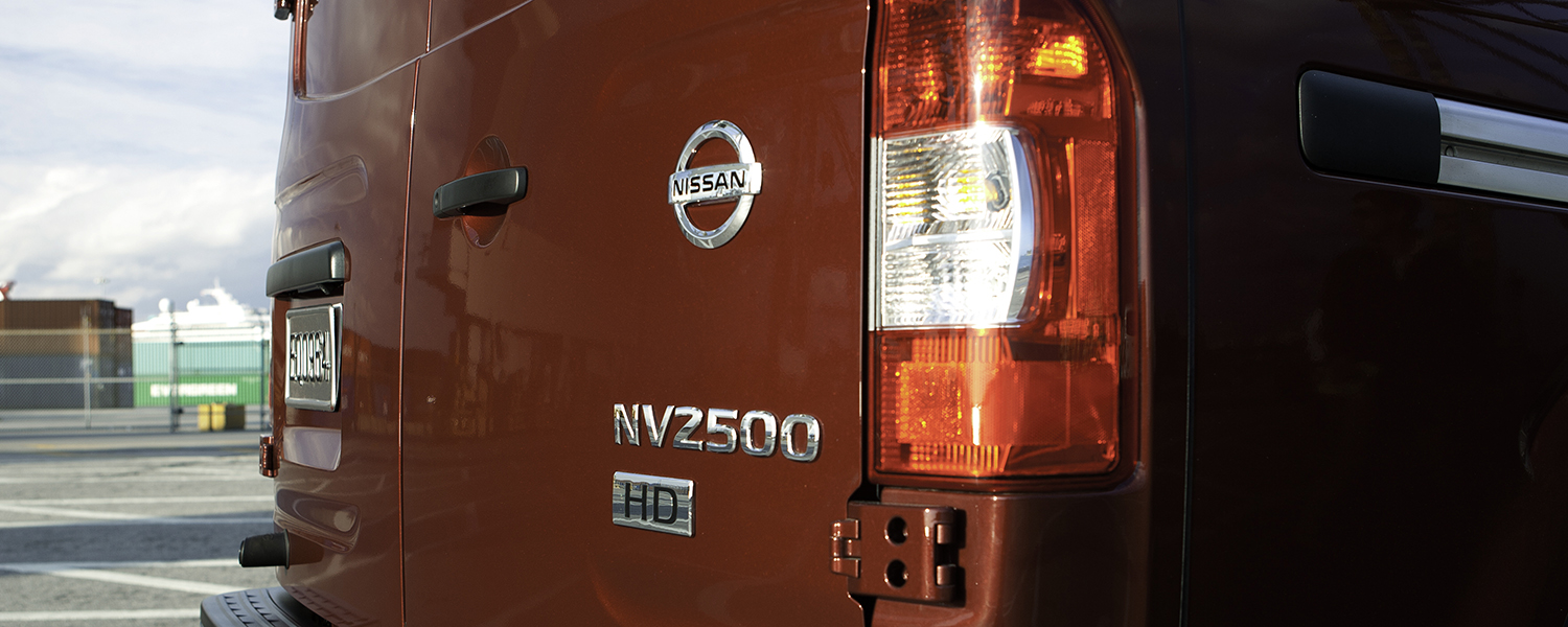 A red Nissan NV200 Cargo Van badge and Nissan emblem