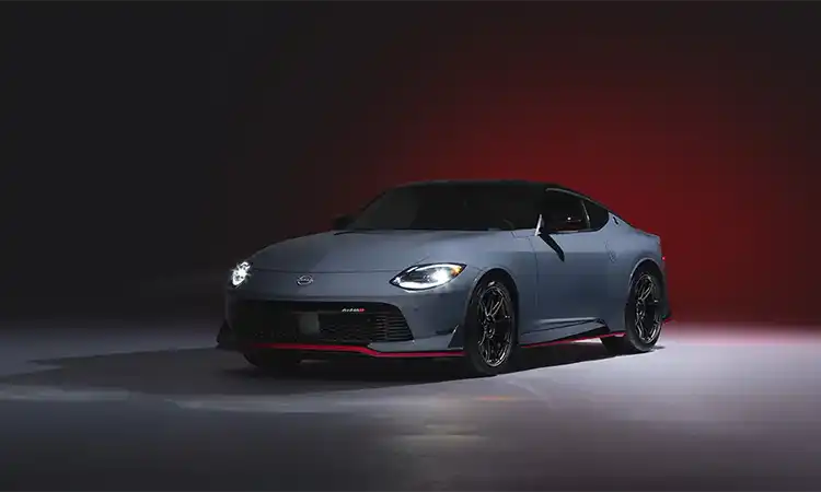 Front left 3/4 angle of a 2024 Z NISMO on a gray floor and dark red gradient background.