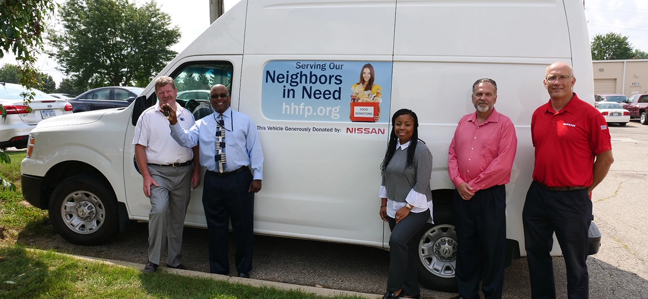 5 people pausing in front of a white van.