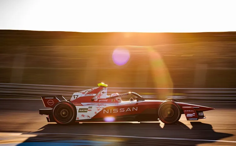 早朝、金色の朝日が差し込み、コースを走行するノーマン ナトーのフォーミュラEマシンに長い影が落ちている。