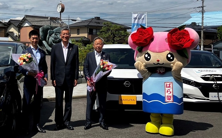 電気自動車の前で記念撮影する各代表者