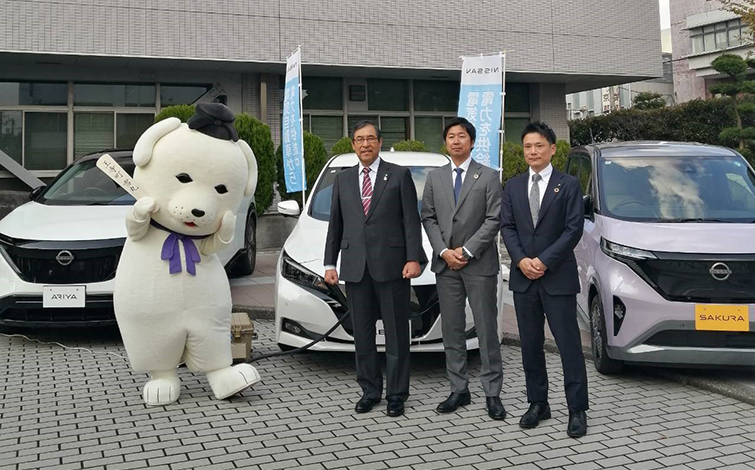 電気自動車の前で記念撮影する各代表者
