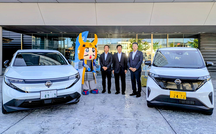 電気自動車の前で記念撮影をする各団体代表者