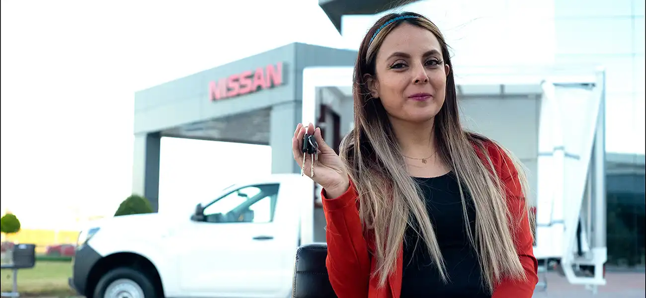 Nallely Flores with her car key standing in front of her NP300 pickup.