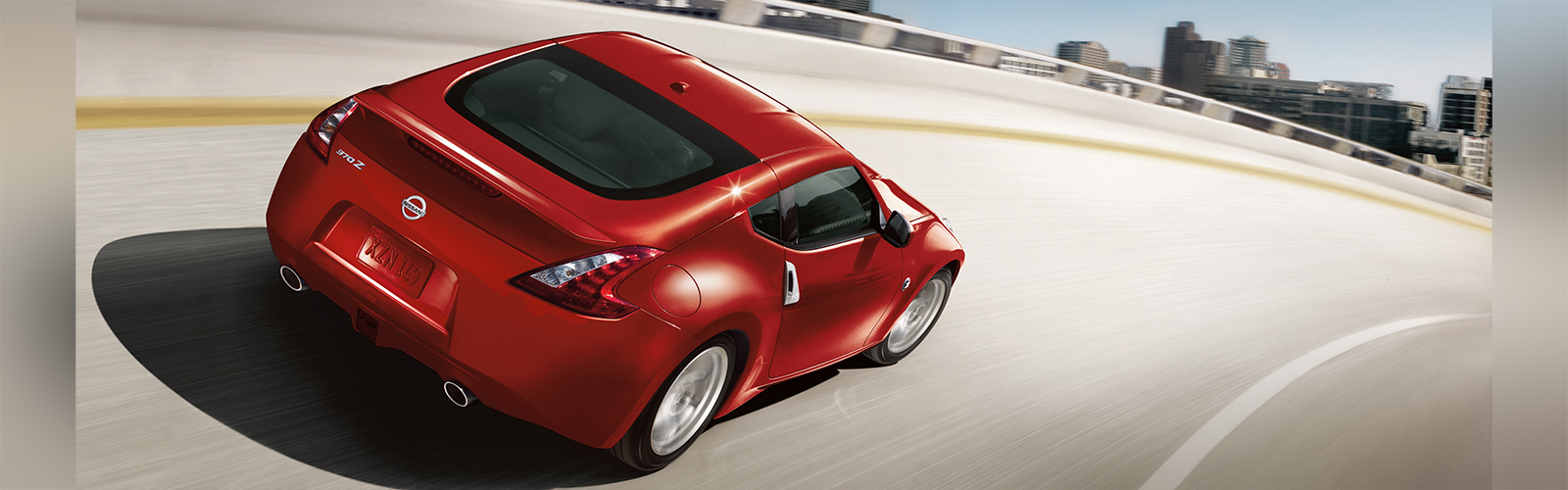 A red Nissan Z coupe driving around a sharp curved road.