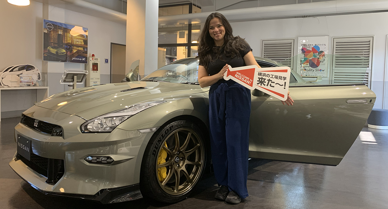 Woman holding sign in front of vehicle in showroom