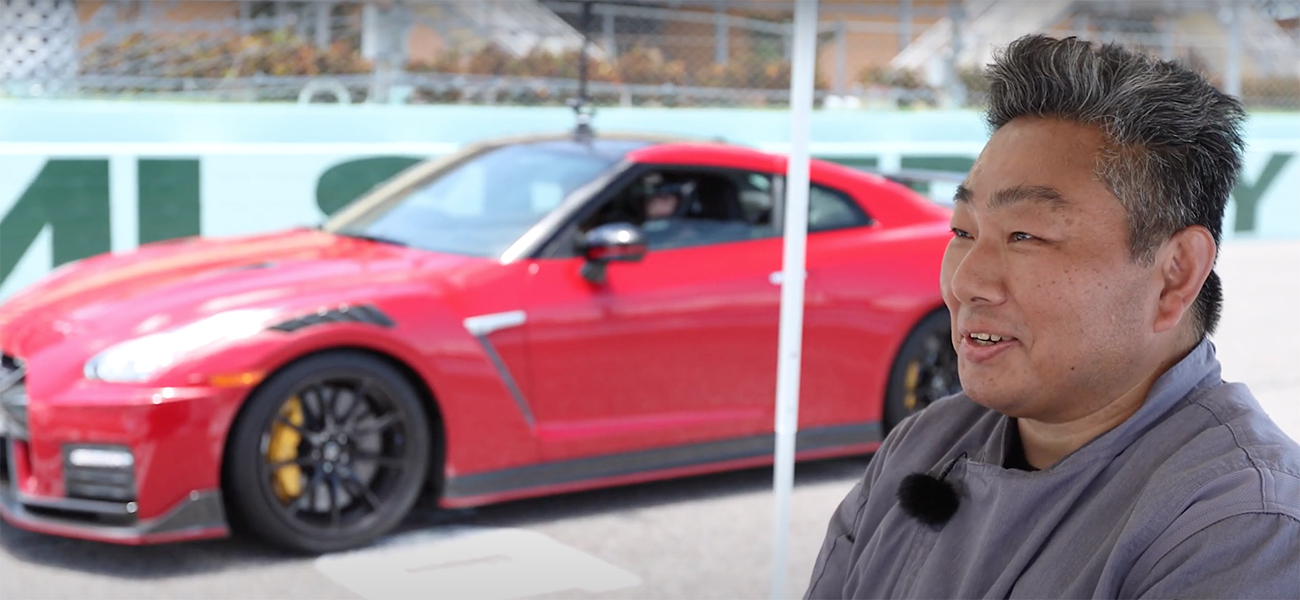 A side profile of a man in front of a red GT-R.