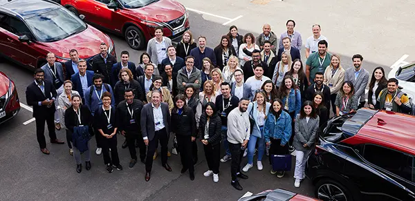 A group of people standing in a parking lot smiling for photo