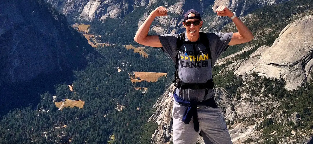 A man pausing at the top of a mountain.