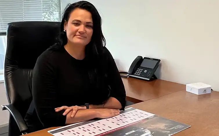Alta Deysel poses for a photo while sitting at a desk.